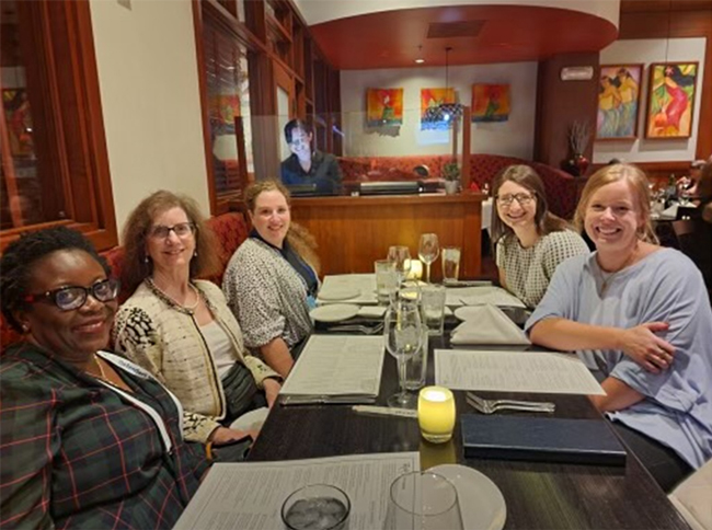 Five medical faculty members sitting at a restaurant table.